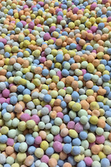 Colorful close-up of assorted candy-coated chocolate or cereal balls in pastel shades. Bright and playful background for confectionery, sweets, party decoration, or children's product themes.