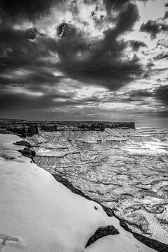 A light snowfall and contrasting darker terrain define the rugged landscape of Canyonlands National Park.