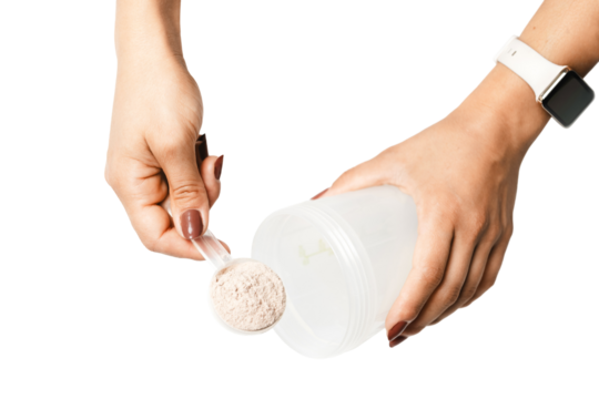 Woman's hands with measuring spoon puts portion of whey protein powder into a shaker, making protein drink cocktail, isolated on transparent background, top view