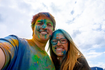 A couple takes a selfie with colored powder on their faces
