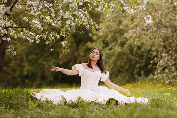 A girl in a dress and a blooming apple tree, taken at sunset