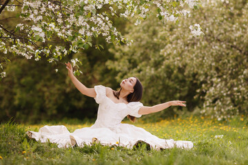 A girl in a dress and a blooming apple tree, taken at sunset
