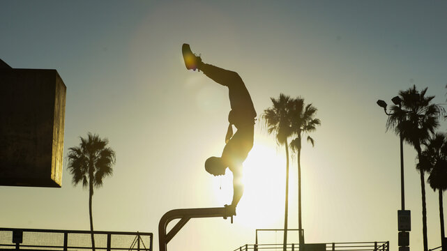 Silhouette of a skilled acrobat performing an impressive handstand on a bar against the stunning backdrop of a glowing sunset.