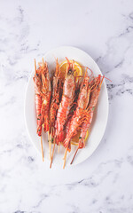 Freshly grilled prawns served, on a white platter ,with lemon slices for a delicious seafood experience