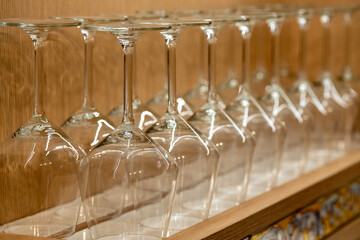 Transparent drinking glasses perfectly lined up on wooden shelves in a restaurant