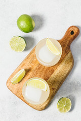 Refreshing detox citrus drink. Vitamin water with lime slices and ice cube on wooden board. Healthy, organic antioxidant drink. Summer lemonade, mocktail, nonalcoholic beverage concept.