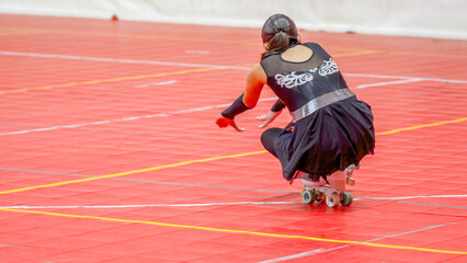 Young woman competing in a roller skating championship wearing a black and silver costume