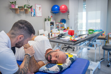Osteopath practising physiotherapy on a couch to a man's shoulder