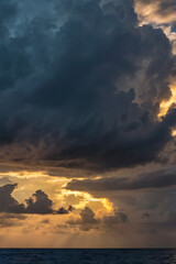 Fototapeta premium Dramatic Sunset Sky Over Ocean Golden Rays Pierce Dark Clouds