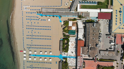 Aerial top-down view of a seaside beach resort with rows of umbrellas and sunbeds in summer