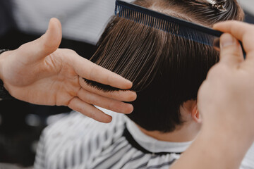 Close-up master hairdresser does hairstyle and style with scissors and comb, Concept Barbershop