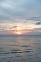 Obraz premium Beautiful sunrise over the ocean with birds soaring through the morning sky. The soft glow of dawn bathes the water and horizon in gentle pastel colors, creating a peaceful and atmospheric coastal sce