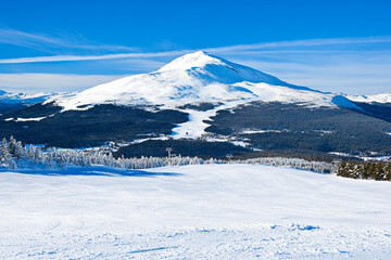 Obraz premium Snow-covered mountain range showcasing winter beauty and outdoor activities near a ski resort surrounded by trees