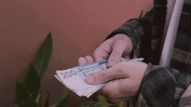 closeup male hands hold Moroccan dirham money, count paper dirham banknotes, concept cash payments, monetary savings, save for vacation, exchange and cashing currency