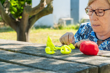 An elderly woman with Alzheimer's has fun making clay figures in the park