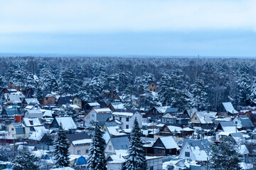 A serene village blanketed in fresh snow showcases a collection of houses, surrounded by dense...