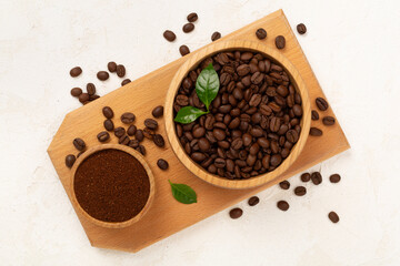 Roasted coffee beans with leaves on concrete background,top view