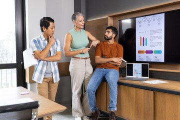 Discussing Diverse colleagues reviewing data on countertop in breakout area, with laptop and screen