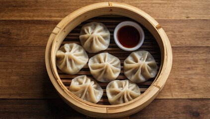Fototapeta premium Realistic top view of traditional Chinese dumplings in a bamboo steamer with dipping sauce on a wooden table, no text or branding.