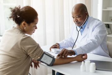 Hypertension Concept. Black Male Doctor Measuring Arterial Blood Pressure Of Female Patient In...