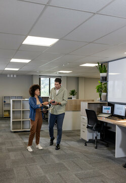 Reviewing Diverse coworkers comparing charts in office space, with tablet and smartphone