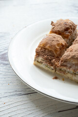 Cold baklava with cacao on a white plate	close up