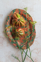 Vibrant tomatoes and fennel flowers on a patterned plate with this rustic setup, ready for social media food posts. Suited for grocery, organic products, or farmer’s market promotions.