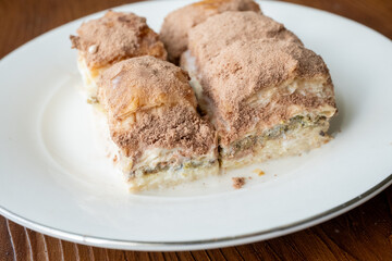 Cold baklava with cacao on a white plate	close up