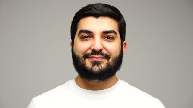 Confident man in a white t-shirt standing against a minimalistic background with an assertive expression