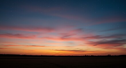 Obraz premium Dramatic sunset with vibrant colors over a dark field under a starry sky
