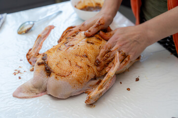 Preparing a marinated duck for cooking in a kitchen setting during daylight hours