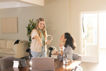 Recording Diverse female colleagues collaborating at table in home office, with podcast microphones