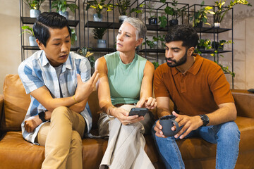 Discussing work, Diverse coworkers sitting on couch in office lounge with smartphone and coffee mug