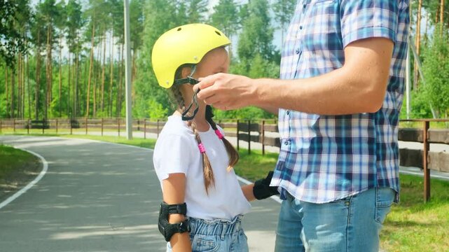 Father helped her daughter wear a yellow helmet while enjoying time together in the park