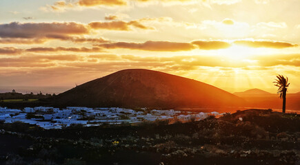 Naklejka premium Sunset over Volcanic Landscape and White Village in Lanzarote