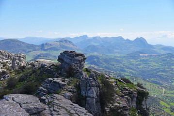 A shot of rock formations with mountains in the back with atmospheric perspective and high vantage point view. Taken in the National Park of El Torcal de Antequera, Spain. 