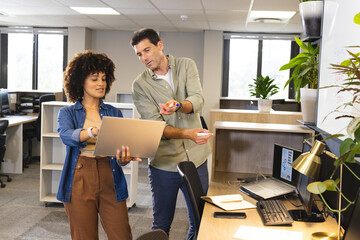 Collaborating Diverse coworkers reviewing data on laptop at open office, with colorful marker pens
