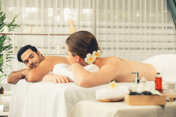 Blissful couple customer having exfoliation treatment in luxury spa salon with warmth candle light...