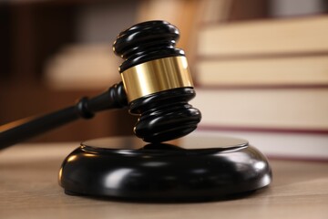 Judge's gavel and books on wooden table indoors, selective focus