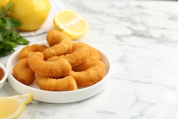 Tasty tempura shrimps and lemon on white marble table, closeup. Space for text