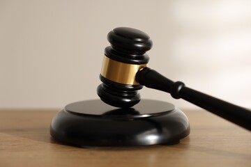 Judge's gavel on wooden table against light background, closeup