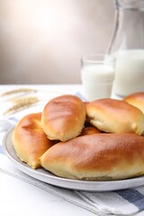 Tasty baked patties and spikelets on white wooden table against grey background, closeup