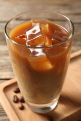 Tasty iced coffee and beans on wooden table, closeup
