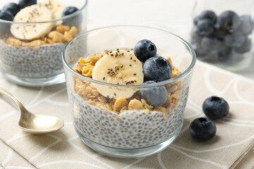 Delicious dessert with chia seeds, yogurt, granola, blueberries and banana on table, closeup. Superfood