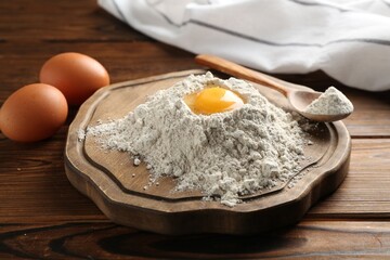Pile of flour and eggs on wooden table, closeup
