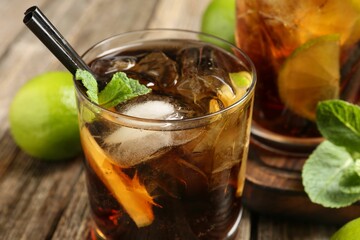Refreshing Cuba libre cocktail with mint on wooden table, closeup