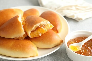 Tasty baked patties with orange jam on light grey table, closeup