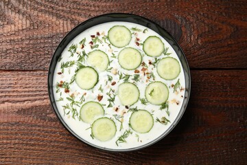 Fresh tasty cucumber soup on wooden table, top view