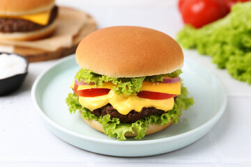 Tasty cheeseburger with lettuce and tomatoes on white table, closeup