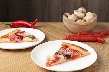 Slices of tasty pizza with thin smoked sausages served on wooden table, closeup
